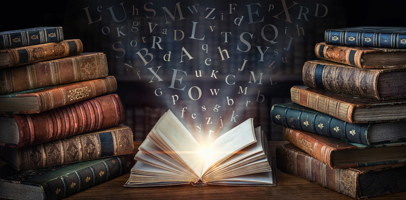 An open book emitting light surrounded by stacks of old books, with letters floating in the air.